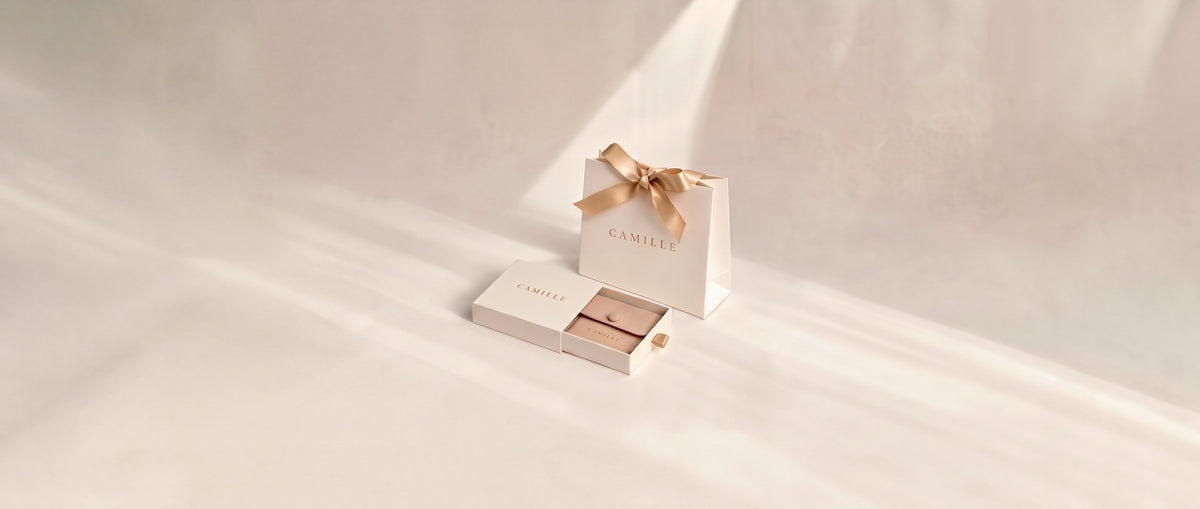 Empaque Camille: bolsa con moño dorado y caja con pouch