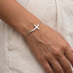 Pulsera Cruz curva plateada puesta
