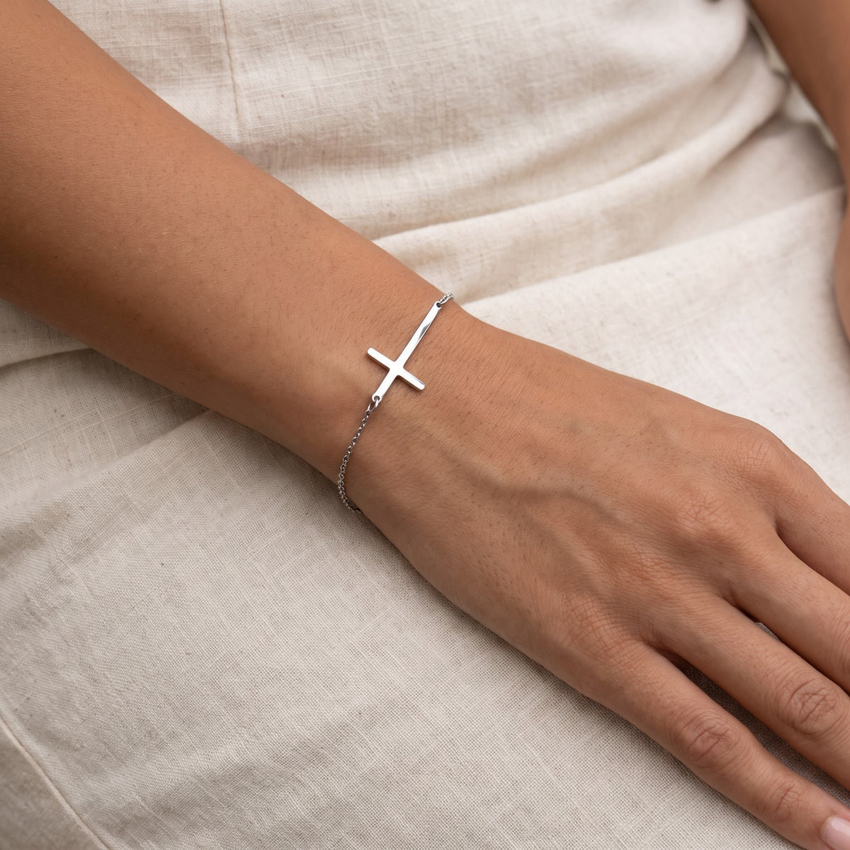 Pulsera Cruz de lado plateada puesta